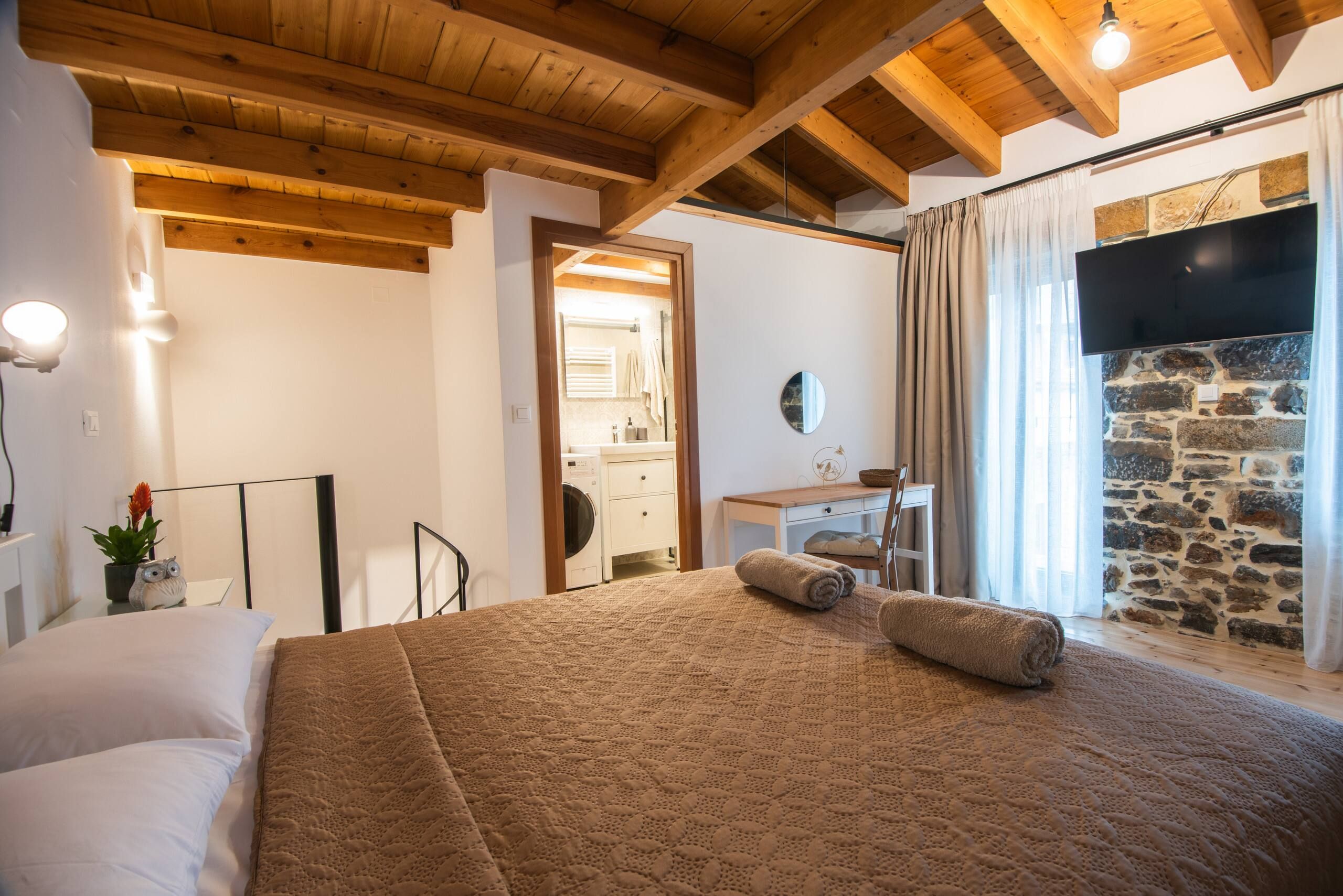 Bedroom with linen curtains and a stone wall