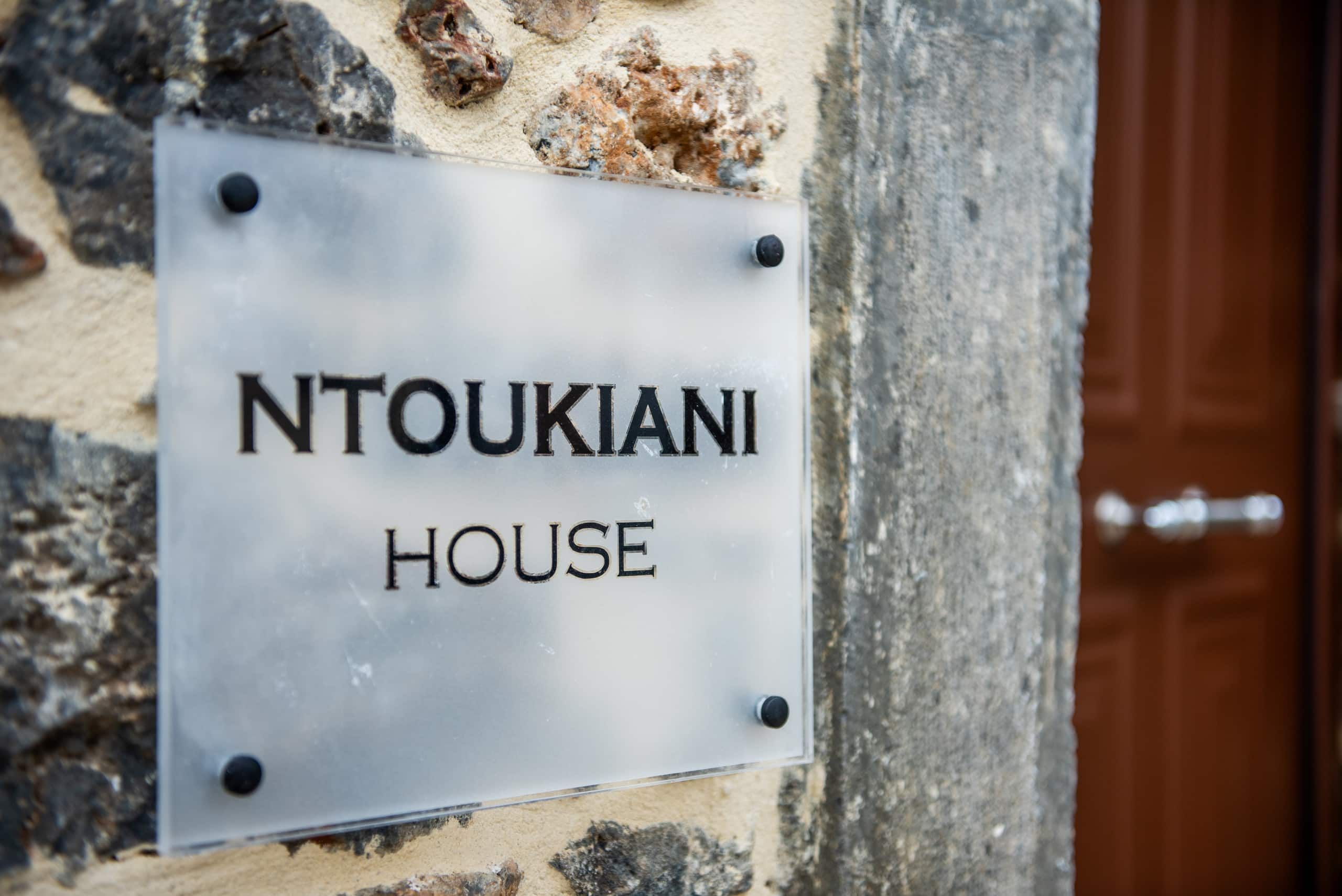 “Ntoukiani House” sign on the stone wall by the door
